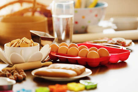 Table with dish of biscuits and ingredients for making biscuits.の写真素材