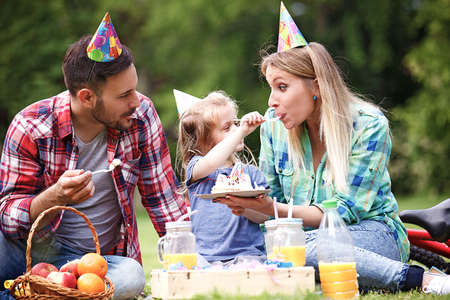 Happy family of three celebrating birthaday party in the park.の写真素材