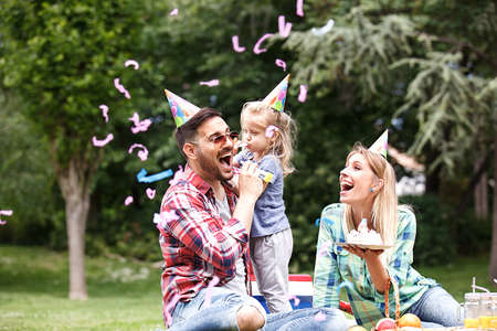 Happy family of three celebrating birthaday party in the park.の写真素材