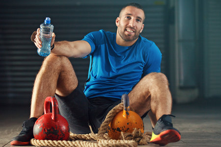 Young strong man is relaxing after training with kettlebell.の写真素材