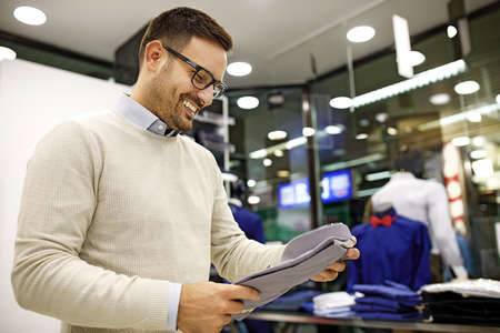 Portrait of handsome young man buying clothes in the store.の写真素材