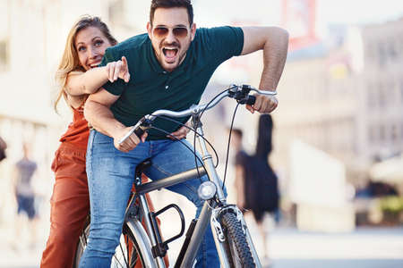 Portrait of happy young couple riding a bike in the city.の写真素材