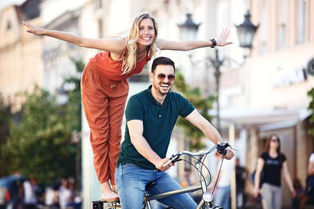 Portrait of happy young couple riding a bike in the city.の写真素材