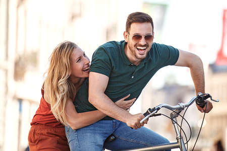 Portrait of happy young couple riding a bike in the city.の写真素材
