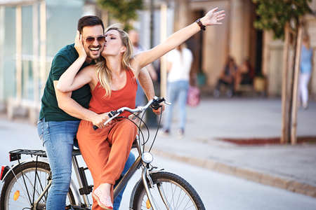 Portrait of happy young couple riding a bike in the city.の写真素材