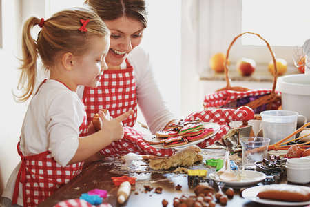 Young mother and her beautiful  daughter making dough for biscuits. Lifestyle photo. の写真素材