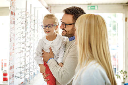 Happy family choosing glasses in optics store.の写真素材