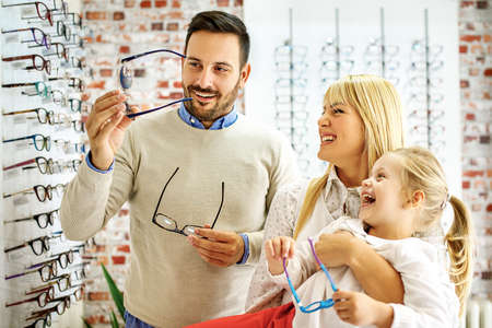 Happy family choosing glasses in optics store.の写真素材