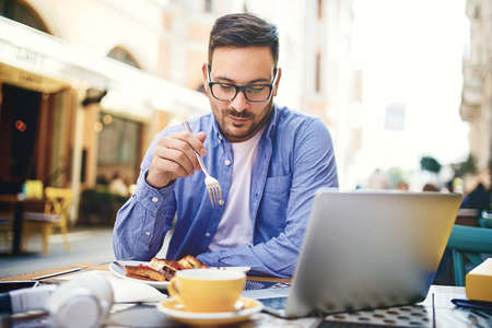 Businessman having breakfast and doing his work in cafe.の写真素材