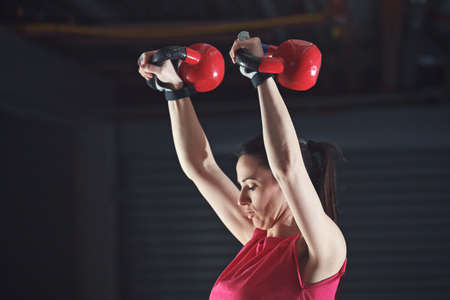 Young athelete woman is training in garage using kettle bell.の写真素材