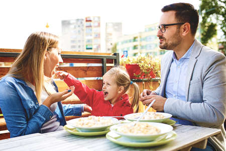 Happy family is enjoying pasta in restaurant.の写真素材