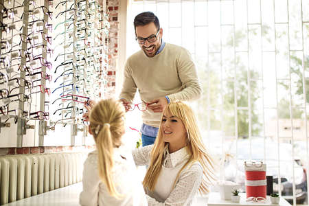 Happy family choosing glasses in optics store.の写真素材