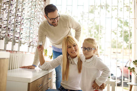 Happy family choosing glasses in optics store.の写真素材