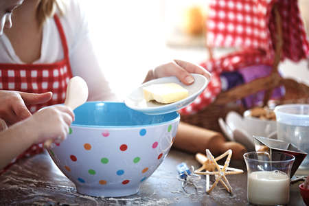 Young mother and her beautiful 4 years old daughter making dough for biscuits.の写真素材