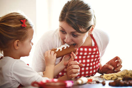 Young mother and her beautiful 4 years old daughter making dough for biscuits.の写真素材