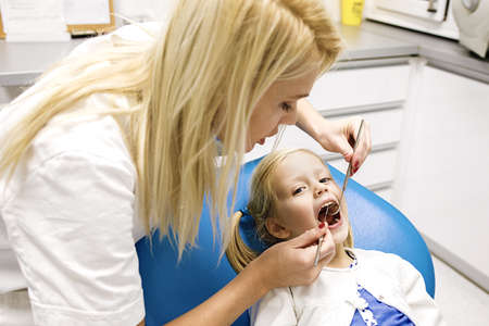 Dentist treating cute blonde child in his surgery.の写真素材