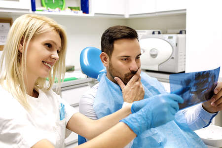 Female dentist and young man patinet in dentist office.の写真素材