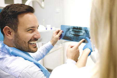 Female dentist and young man patinet in dentist office.の写真素材