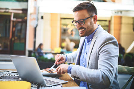Businessman having breakfast and doing his work in cafe.の写真素材