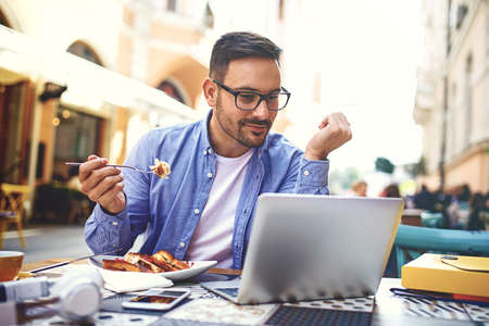 Businessman having breakfast and doing his work in cafe.の写真素材