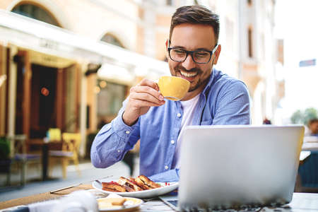 Businessman having breakfast and doing his work in cafe.の写真素材