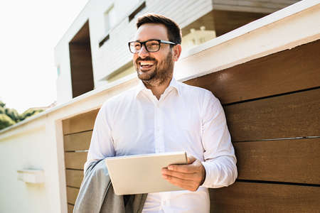 Young smiling businessman is using tablet outside.の写真素材