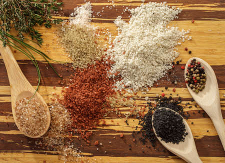 different salts on a wooden table with pepperの写真素材