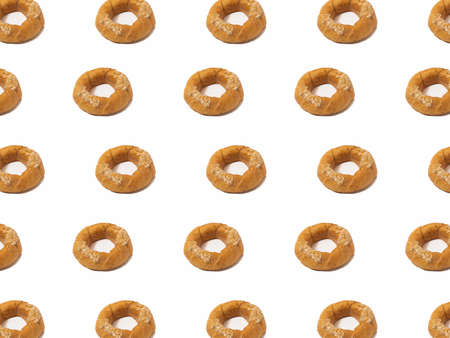 Trendy white pattern made of rolls bagel with sesame. White background. Minimal concept. Cool bakery food.の写真素材