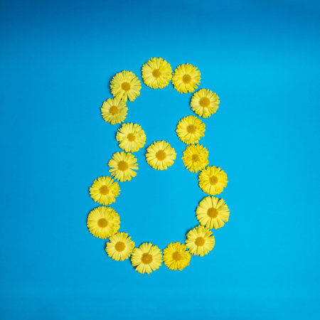 Number eight 8, made of yellow flowers. Blue background.