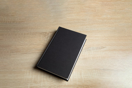 Black book on wooden background.