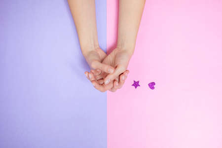 Two woman s hands on pink and purple background. Little shine purple star and heartの写真素材