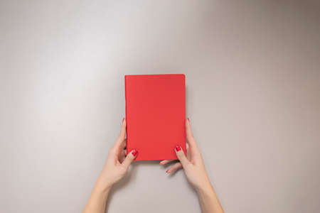a red book in beautiful female hands. Bright background. useful photography.の写真素材