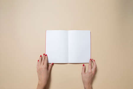 open notebook and beautiful female hands, on a light brown backgroundの写真素材