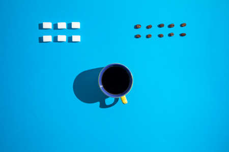 Sugar cubes, yellow a cup of coffee and coffee beans on a blue background. Great, cool and minimalistic look.の写真素材