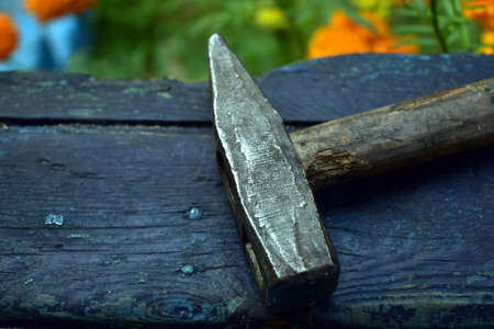 old hammer with a wooden handle lies on a blue boardの写真素材
