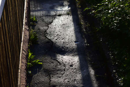 wet cracked asphalt, path near the house at dawnの写真素材