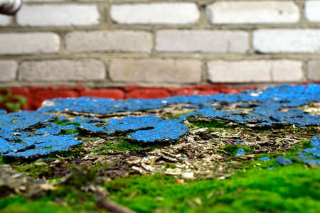 old chipboard with remnants of blue paint against a brick wallの写真素材