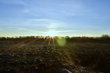 rays of the sun over a field covered with frostの写真素材