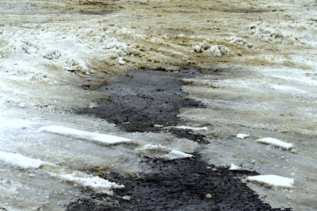 the asphalt appeared from under the snow on the roadの写真素材