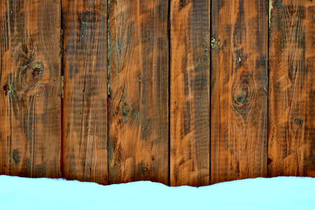 snow and a wall of dark wooden boardsの写真素材