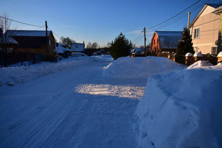 snow-covered village street in the contrasting light of the morning sunの写真素材