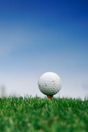 Golf ball on the grass over blue skyの写真素材