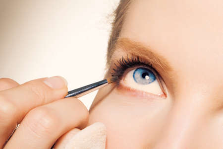 Charming young woman applying blusher eyelidの写真素材