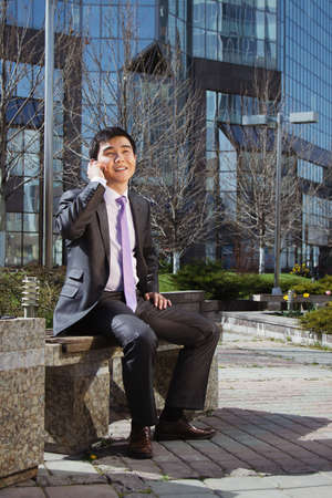 Young businessman sitting and talking on mobile phone.の写真素材