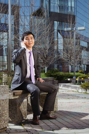 Young businessman sitting and talking on mobile phone.の写真素材
