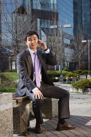 Young businessman sitting and talking on mobile phone.の写真素材