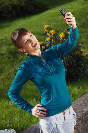 Woman posing for a photograph taken from his cell phoneの写真素材