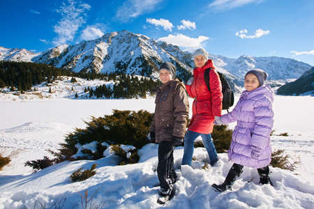 Family (mother with two children) take a walk on winter mountain slope (Big Almaty Lake, Kazakhstan)の写真素材