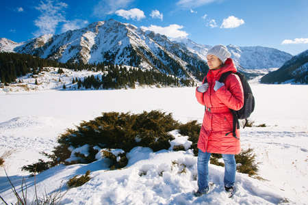 Young woman take a walk on winter mountain slope (Big Almaty Lake, Kazakhstan)の写真素材