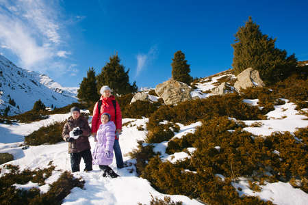 Family (mother with two children) take a walk on winter mountain slope (Big Almaty Lake, Kazakhstan)の写真素材